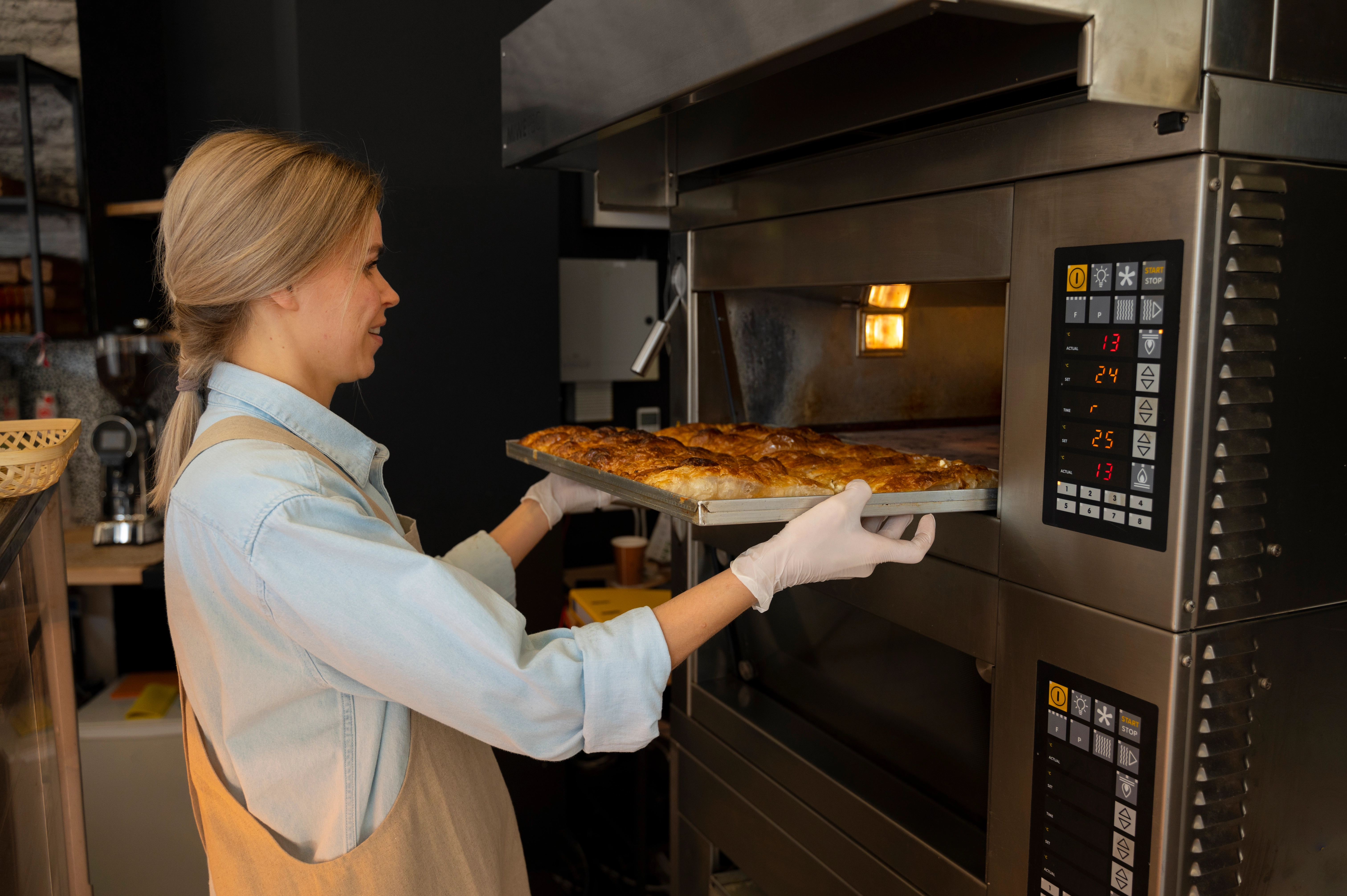 Chef using a commercial oven in a professional kitchen to bake food, showcasing high-capacity ovens for restaurants and bakeries.